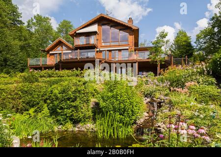 Retro di pezzo colorato dorato-marrone sul pezzo orientale pino bianco tronco e legname casa e giardino inclinato cortile con cascata cascata e ruscello. Foto Stock