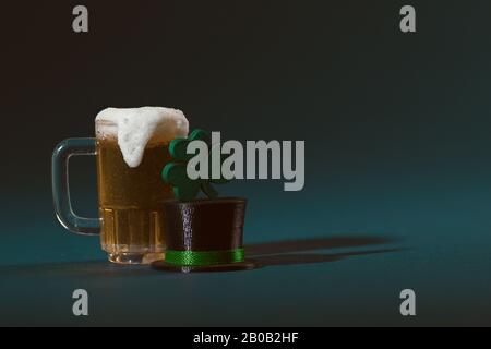 Tazza di birra, cappello Leprechaun e Trifogli A Quattro foglie su sfondo verde Foto Stock