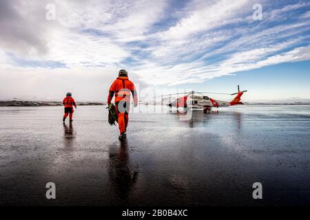 Coast Guard Aids to Navigation (ATON) Team Kodiak equipaggio camminare verso un MH-60 Jayhawk elicottero a Cold Bay, Alaska, 10 gennaio 2020. I membri DI ATON schierano a bordo degli elicotteri alle strutture di supporto dell'aviazione intorno all'Alaska per servire e mantenere gli aiuti di navigazione. Gli equipaggi degli elicotteri sono vitali per far arrivare il personale alle postazioni remote dell'Alaska che non sono facilmente accessibili. Foto della Guardia Costiera degli Stati Uniti di Petty Officer 1st Classe Bradley Pigage. Foto Stock