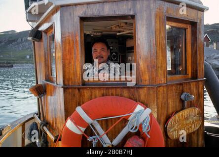 GROENLANDIA, JAKOBSHAVN, PESCATORE NATIVO SUL PONTE DI BARCA Foto Stock