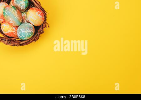 Le uova di pasqua Colofeful nel nido su sfondo di colore giallo. Foto Stock