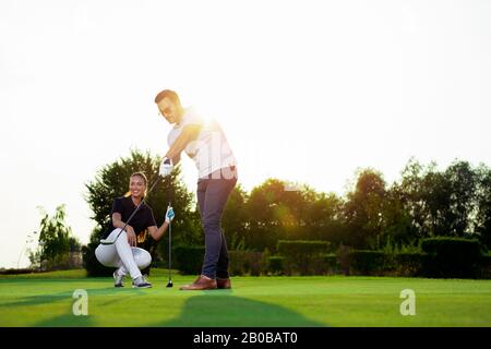 Un golfer maschio attraente sta provando a mettere la sfera nel foro, ma non è riuscito. Foto Stock