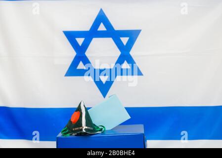 Elezioni Israele. Maschera facciale respiratoria batterica in una scatola per le elezioni in Israele sfondo bandiera. Gli israeliani messi in quarantena per il coronavirus avranno le cabine di voto per le elezioni di marzo. Foto Stock
