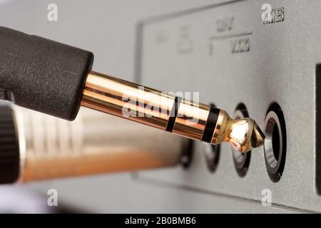 Collegamento del connettore audio della presa telefonica dorata TRS collegato alla presa del dispositivo audio. Musica, audio, hi-fi, connettività e riproduzione audio. Foto Stock