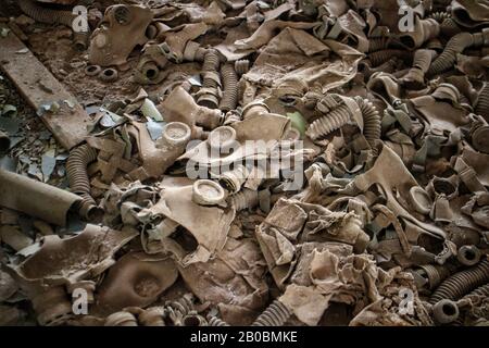 Un mucchio di maschere a gas dell'era sovietica in un edificio abbandonato a Pripyat, in Ucraina, sede del desaster nucleare di Chernobyl del 1986. Foto Stock