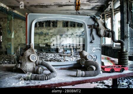 Le maschere a gas dell'era sovietica sono appese su uno schermo TV a resistenza agli agenti atmosferici in un edificio abbandonato a Pripyat, in Ucraina, sito del desaster nucleare di Chernobyl del 1986. Foto Stock