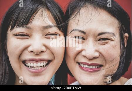 Ritratto di madre asiatica e figlia ridere di fronte alla macchina fotografica - Famiglia persone che hanno divertimento all'aperto - Maternità, felicità e teneri momenti concep Foto Stock