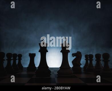 Gioco di scacchi concetto di sfida, idee e concorrenza. Personaggi di scacchi isolati con sfondo scuro con nebbia e luce bianca Foto Stock