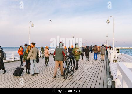 Una folla di persone cammina su un molo di legno a Sopot, Polonia, il 20 luglio 2020 in una soleggiata giornata invernale vicino al Mar Baltico. Vacanza invernale vicino al Foto Stock