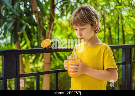 Ragazzo carino che beve succo d'arancia per colazione Foto Stock