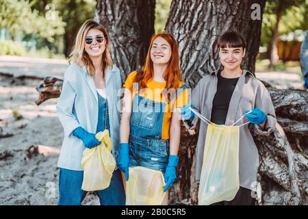 Amici che raccolgono rifiuti dal parco. Essi raccolgono la lettiera in sacco di spazzatura Foto Stock