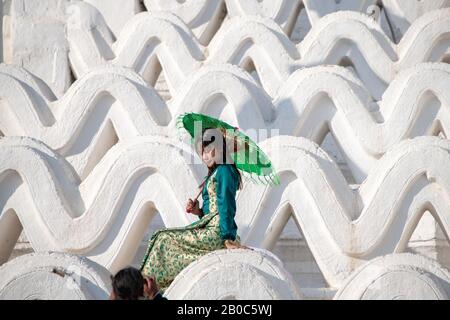 Mingun, Myanmar - Gennaio 2020: La ragazza in un vestito verde pone per le foto contro le terrazze ondulate alla Pagoda di Hsinbyume. Foto Stock