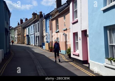 Donna Hiker camminare lungo Irsha Street una Stretta strada di Color Pastello Case Terrazzate in Appledore sul South West Coast Path. Devon Nord. Foto Stock