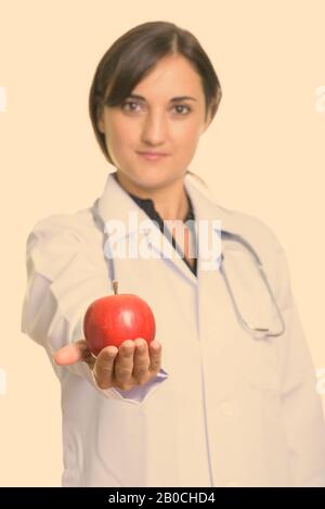 Primo piano di bella donna medico che dà mela rossa con fuoco sulla mela Foto Stock