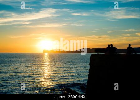 Alghero, ITALIA - 17 SETTEMBRE 2017: Persone che guardano il tramonto sul Mar Mediterraneo alle mura del centro storico di Alghero, Sardegna, Italia Foto Stock