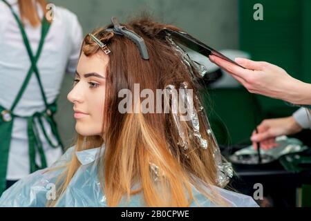 Giovane donna che riceve i capelli tinteggiatura da estetista nel salone dei capelli. Foto Stock