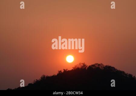 Impressionante alba su silhouette di foresta nera e colline di si Racha, nell'ora della mattina presto, alberi neri sotto il cielo rosso arancio Foto Stock