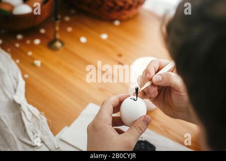 Mani pittura uovo di pasqua con cera calda sullo sfondo di tavola di legno. Moderne uova di Pasqua con eleganti ornamenti in cera. Buona Pasqua. Zero sprechi. Ucraino Foto Stock