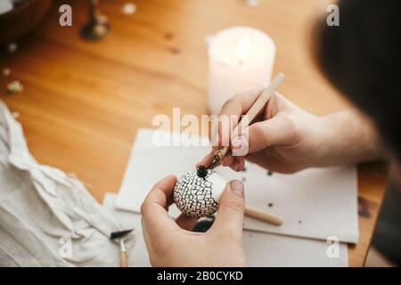 Mani pittura uovo di pasqua con cera calda sullo sfondo di tavola di legno. Moderne uova di Pasqua con eleganti ornamenti in cera. Buona Pasqua. Zero sprechi. Ucraino Foto Stock