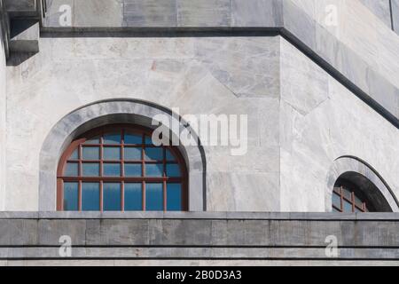 Le finestre ad arco in legno sull'edificio in marmo riflettono il cielo blu in una giornata di sole Foto Stock