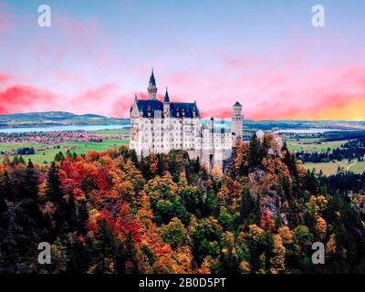 Il famoso castello di Neuschwanstein al tramonto, con un colorato panorama della montagna sullo sfondo Foto Stock