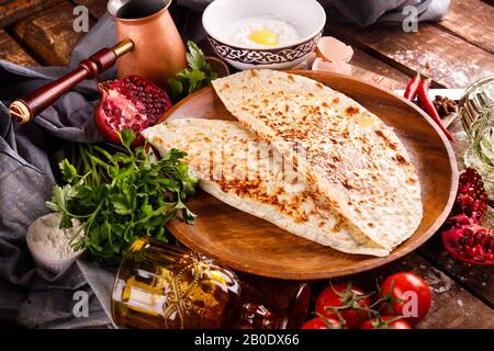 La cucina nazionale azerbaigiana si distingue per i kutabs su un piatto. Vista dall'alto e sfondo in legno Foto Stock