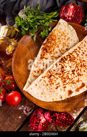 La cucina nazionale azerbaigiana si distingue per i kutabs su un piatto. Vista dall'alto e sfondo in legno Foto Stock