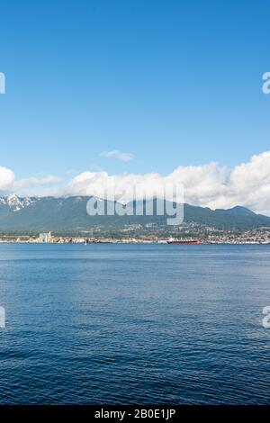 Vancouver, British Columbia, Canada - Dicembre, 2019 - Vista sulle montagne con nuvole in una Splendida giornata di cielo blu al porto marittimo della costa occidentale. Foto Stock