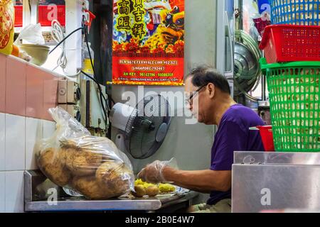 Uomo che lavora in un negozio di cucina dietro preparare verdure e cibo da servire nel ristorante, Chinatown, Singapore, Asia, Foto Stock