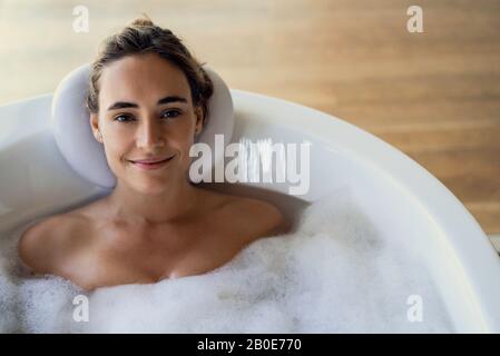 Giovane donna relax nella vasca da bagno Foto Stock