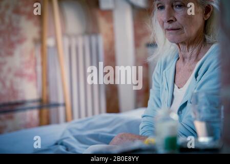 Senior donna seduta sul letto Foto Stock