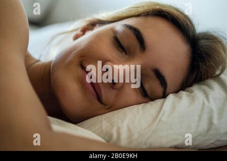 Giovane donna che dorme sul letto Foto Stock