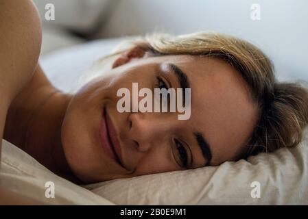 Giovane donna che dorme sul letto Foto Stock
