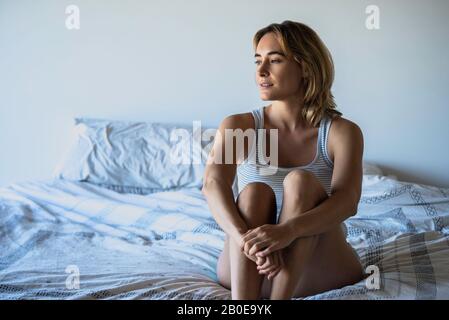 Donna seduta sul letto Foto Stock