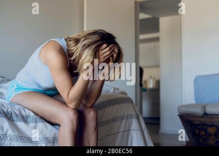Donna stressata seduta a letto Foto Stock