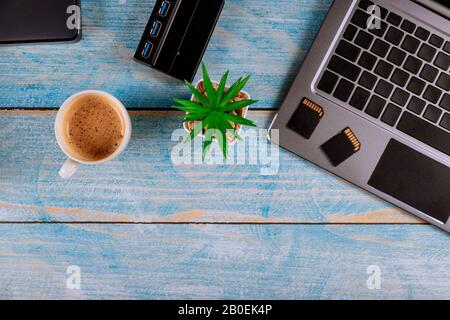 Scrivania per fotografi di lavoro in ufficio con computer portatile con disco rigido esterno, scheda SD caffè, occhiali vista dall'alto Foto Stock