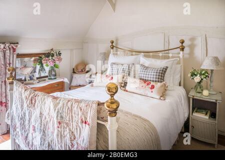 Patchwork trapunta di Debbie In Giù fatto da resti di tessuti preferiti, su letto in ferro battuto Gingham cuscini e rose rosse su letto in ferro battuto Foto Stock