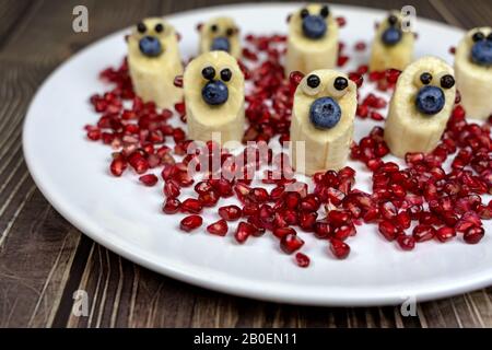 divertenti piccole cifre di orsetto di banana su piatto bianco sano dessert per i bambini Foto Stock