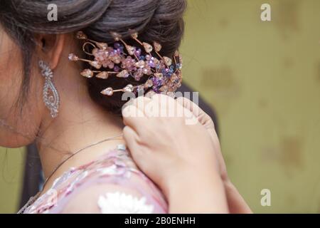 Sposo che porta una collana alla sposa. Madre della sposa che aiuta a vestire la collana sua bella figlia in interni . Sposa che indossa una collana . Lui Foto Stock