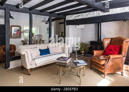 Pavimento in erba di mare con pulsante vittoriano divano posteriore con sedia ad ala in pelle olandese e decorativo metà secolo francese metallo e caffè in vetro Foto Stock