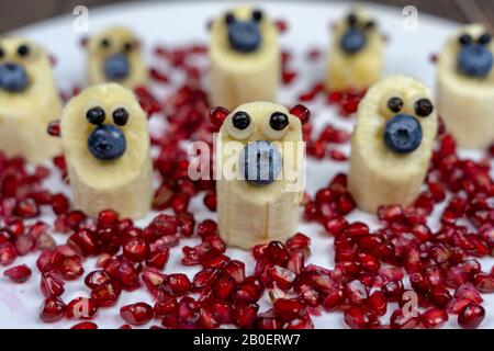 divertenti piccole cifre di orsetto di banana su piatto bianco sano dessert per i bambini Foto Stock