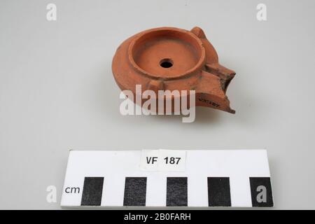 Lampada in terracotta modello rotondo allungato con eccellente beccuccio rotondo (ora demolito), forma sagomata. Sulla parte superiore di una sporgenza rotonda goffrata, che continua sul collo. A lato della sporgenza rotonda 2 protrusioni come rudimenti di picchetti, come si verificano in quei luoghi con lampade di bronzo. Foro antincendio, foro di riempimento e foro dell'aria. Sotto goffrato il marchio PASSOS., lampada ad olio, frammento, terracotta, terracotta, 8 x 6,1 x 3 cm, roman 100-250, Paesi Bassi, Utrecht, Bunnik, Vechten, Housense Vlakte Foto Stock