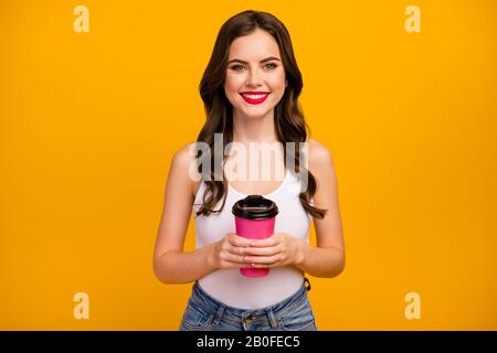 Foto di divertente bella signora tenere carta rosa takeout tazza di caffè calda bevanda passare tempo libero tempo libero gioicing indossare bianco tank-top jeans isolato luminoso Foto Stock