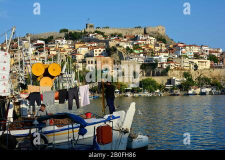 Kavala, Grecia - settembre 17th 2015: Uomini pescatori non identificati su un peschereccio da traino nel porto della città di Eastmacedonia, fortezza ed edifici in backgro Foto Stock