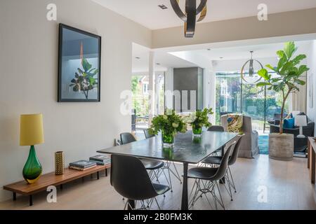 Lampada a sospensione classica in sezioni di ottone e bronzo sopra il tavolo da pranzo in rovere tinto ebano su gambe in bronzo Foto Stock