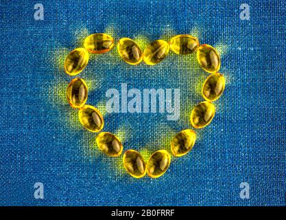 Giallo capsule di gelatina a forma di cuore. copia spazio. vitamine D, omega 3, E. SALUTE Foto Stock