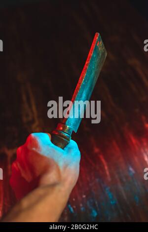 Mano maschio con sfaldatura sopra tavola di legno di notte. Foto Stock