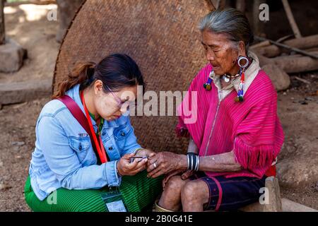 Una Guida Turistica Taglia Le Unghie Delle Dita Di Una Donna Anziana Dal Gruppo Etnico Di Kayaw, Villaggio Di Htay Kho, Loikaw, Myanmar. Foto Stock