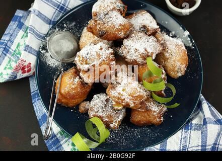 Concetto di cibo italiano. Vista dall'alto dei dolci tradizionali del carnevale fatti in casa: Frittelle italiane di Carnevale con sultanina su sfondo scuro. Foto Stock