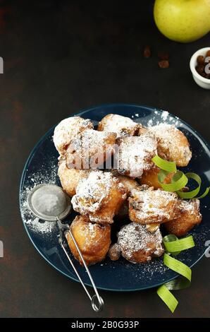 Concetto di cibo italiano. Vista dall'alto dei dolci tradizionali del carnevale fatti in casa: Frittelle italiane di Carnevale con sultanina su sfondo scuro. Foto Stock